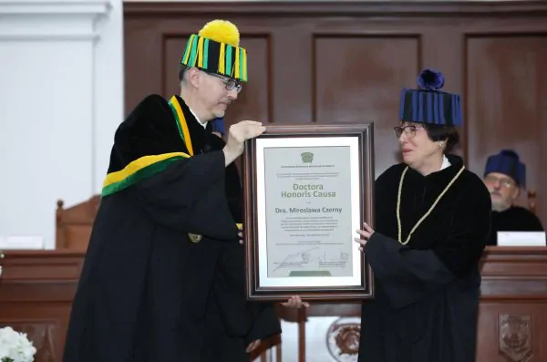 zdjęcie przedstawia Panią Dyrektor, która w uroczystym stroju odbiera nagrodę honoris causa